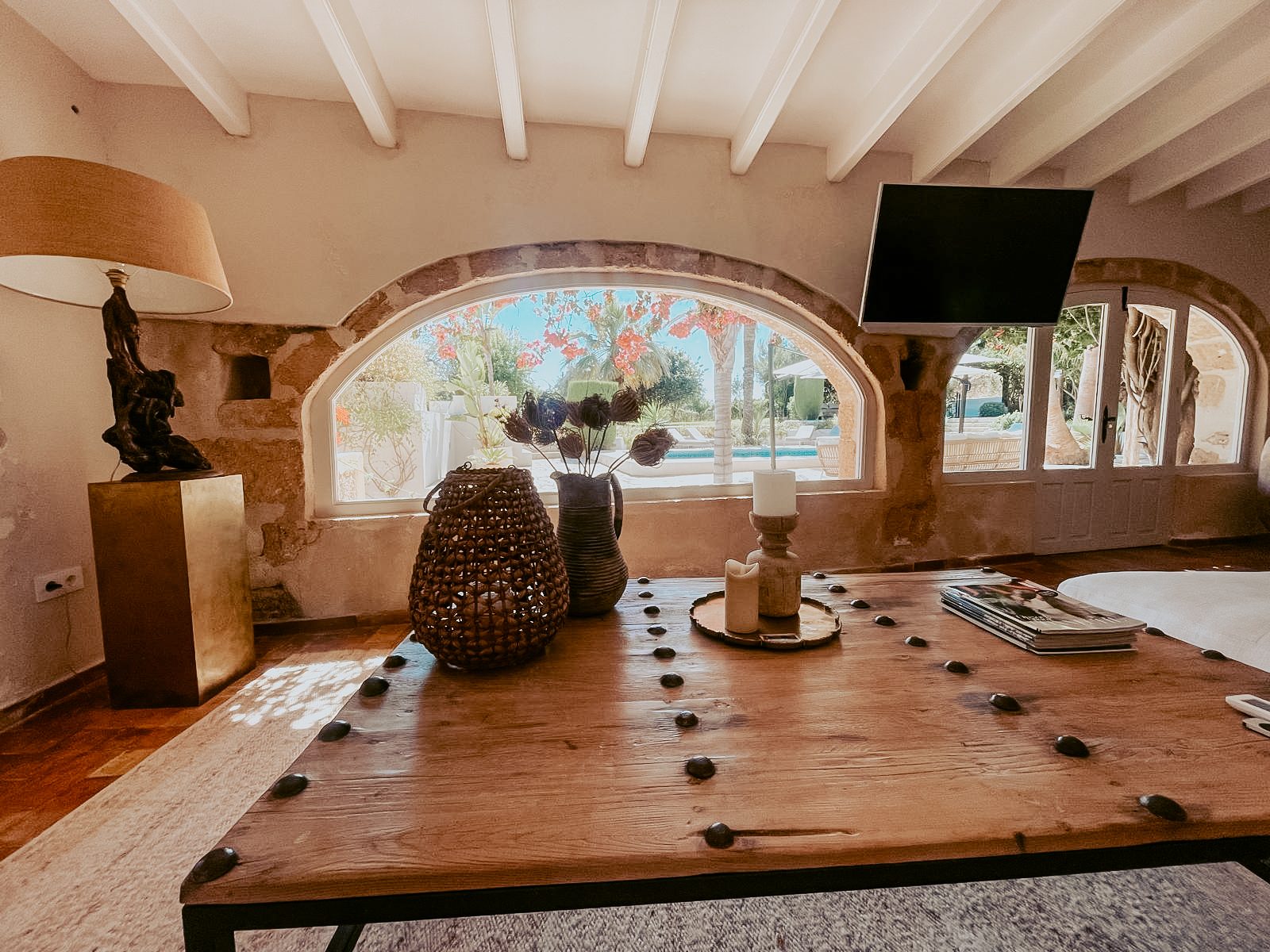 Zithoek met massief houten salontafel en boogvenster op het zwembad